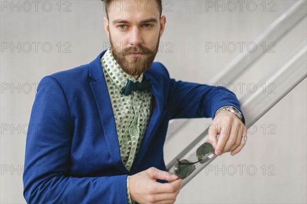 Stylish Middle Eastern man with beard holding sunglasses