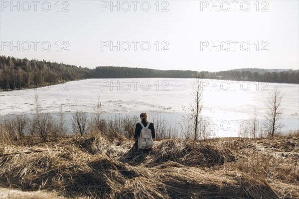 Middle Eastern woman sitting in grass near lake