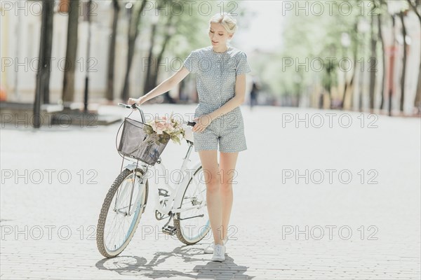 Middle Eastern woman holding bouquet and walking bicycle