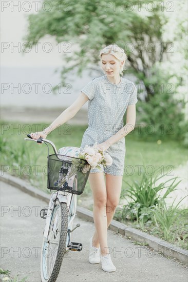 Middle Eastern woman holding bouquet and walking bicycle