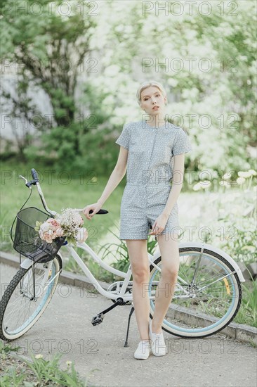 Middle Eastern woman holding bouquet and standing with bicycle