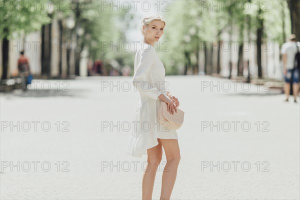 Middle Eastern woman standing in street holding purse