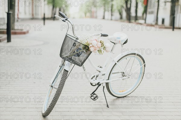 White bicycle on street with flowers in basket