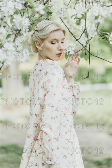 Middle Eastern woman smelling flowers on tree