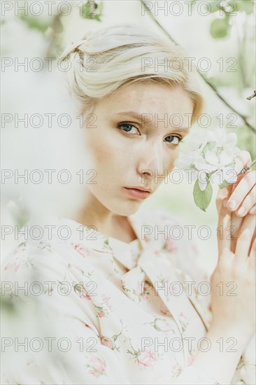 Middle Eastern woman holding flowers on tree