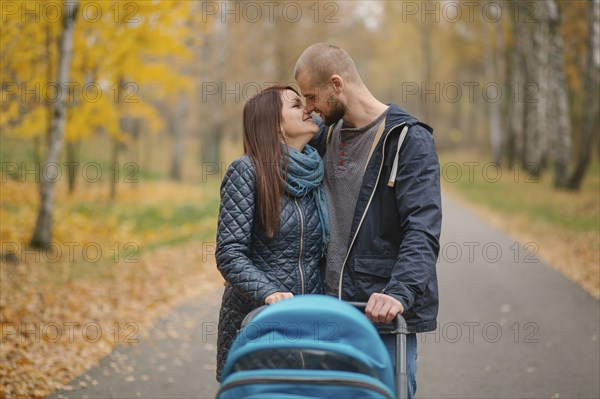 Affectionate Middle Eastern couple with stroller in park