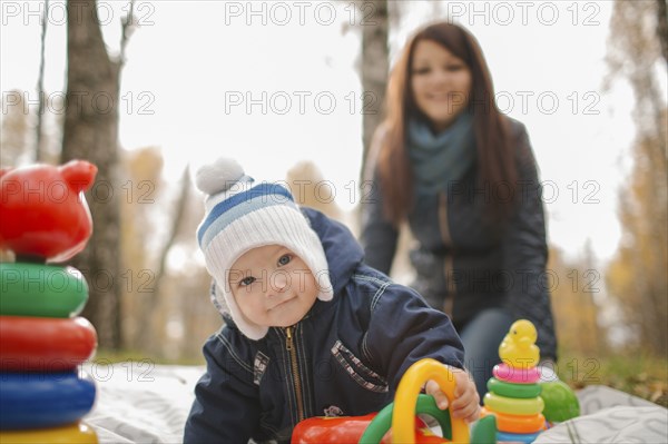 Middle Eastern mother watching baby son playing with toys in park