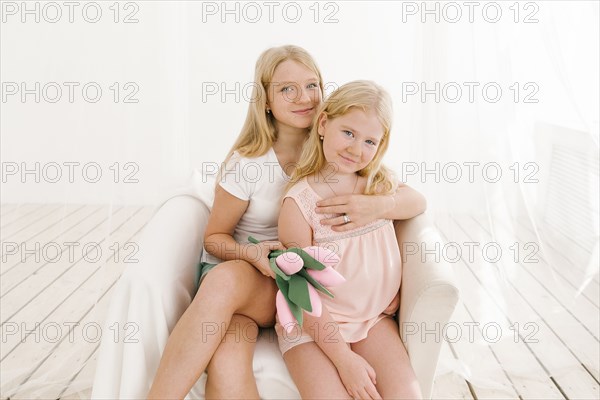 Portrait of smiling Middle Eastern sisters in armchair