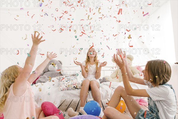 Middle Eastern sisters throwing confetti in bedroom