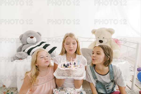 Middle Eastern sisters extinguishing candles on birthday cake