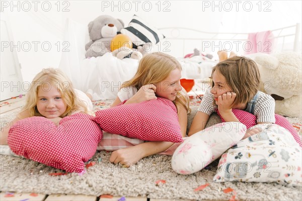 Smiling Middle Eastern sisters laying on floor talking