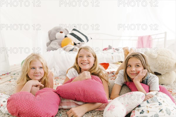 Smiling Middle Eastern sisters laying on floor