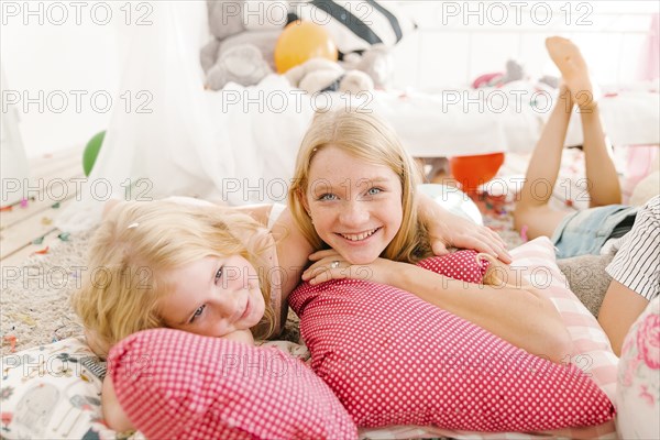 Smiling Middle Eastern sisters laying on floor