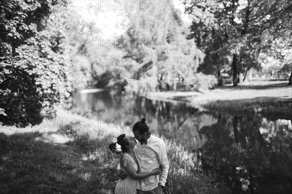 Middle Eastern couple hugging in park near river