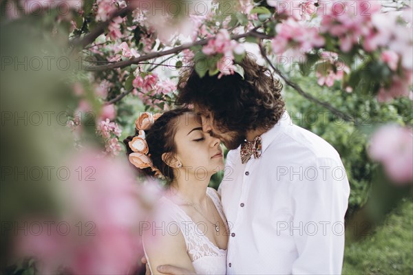Middle Eastern couple kissing under flowering tree
