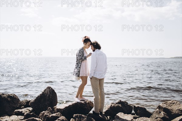 Middle Eastern couple standing on rocks near ocean