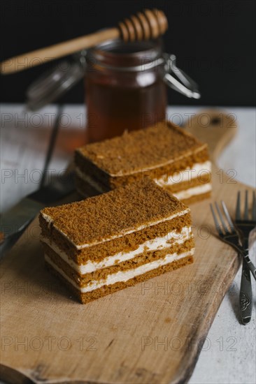 Slices of layer cake on cutting board with honey