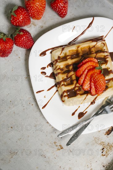 Sliced strawberries and chocolate syrup on waffle