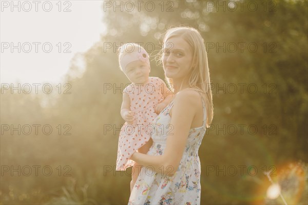 Mother holding baby daughter on sunny day