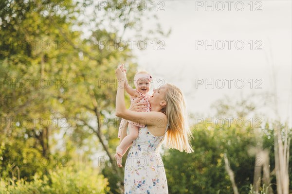 Mother playing with baby daughter on sunny day