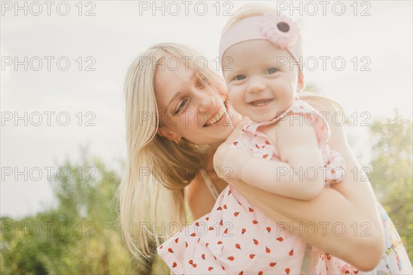 Mother hugging baby daughter on sunny day