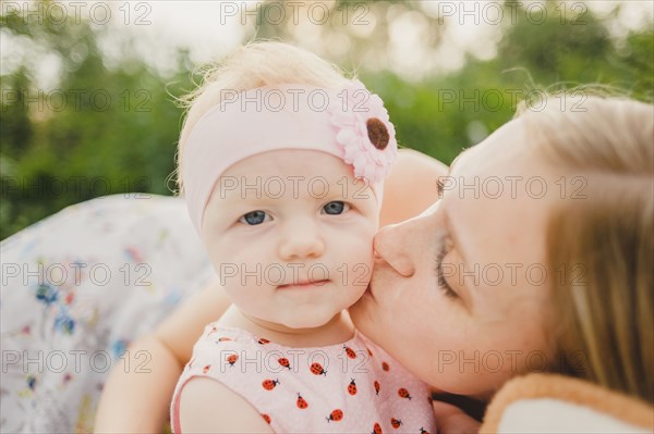 Mother kissing baby daughter on cheek