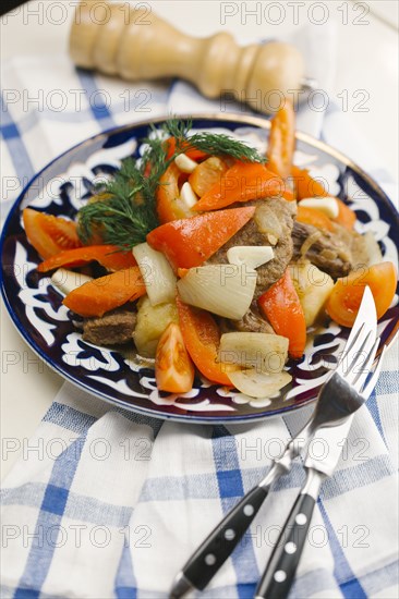 Meat and vegetables on plate with fork and knife