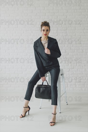 Portrait of glamorous Middle Eastern businesswoman sitting on stool