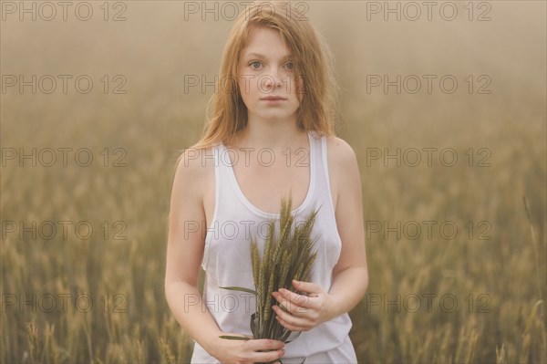 Middle Eastern teenage girl holding wheat in field