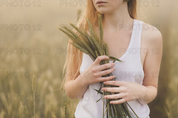 Middle Eastern teenage girl holding wheat in field