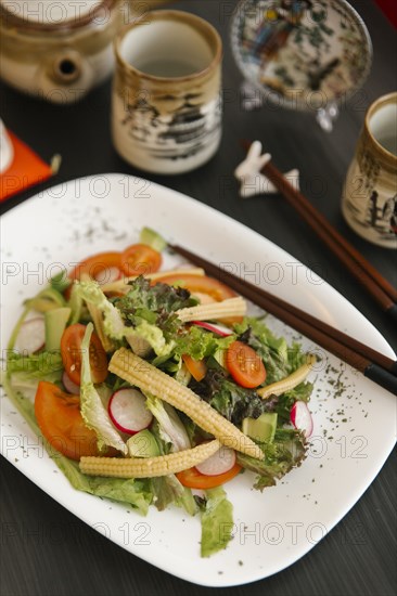 Chopsticks on plate of salad