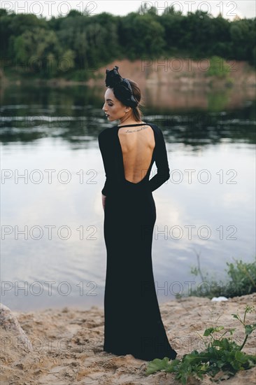 Middle Eastern woman wearing black dress near lake