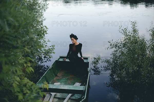 Middle Eastern woman wearing black dress in boat on lake