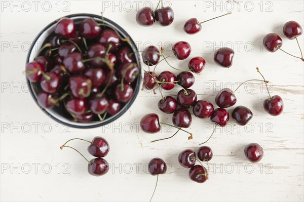 Cherries and bowl on white wooden table