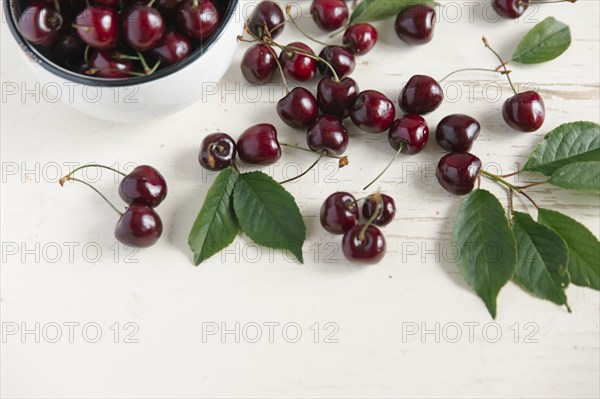 Cherries and bowl on white wooden table