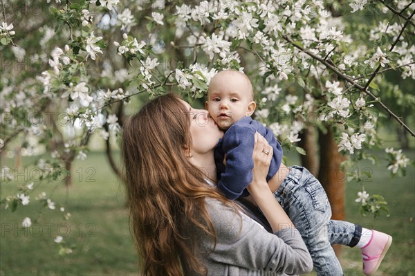 Middle eastern mother kissing son under flowering tree