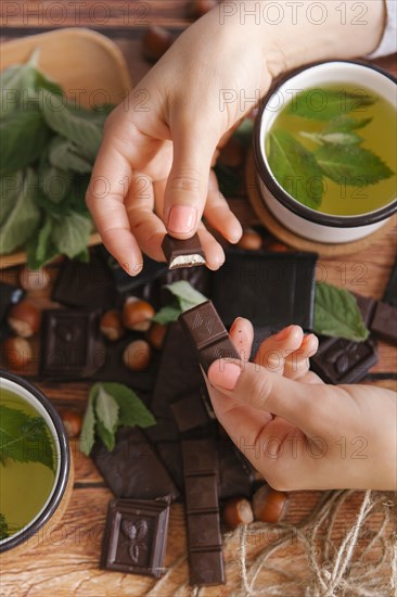 Hands of woman breaking chocolate near green tea