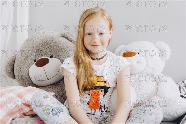 Smiling Middle Eastern girl sitting with large teddy bears