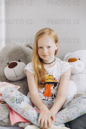 Smiling Middle Eastern girl sitting with large teddy bears