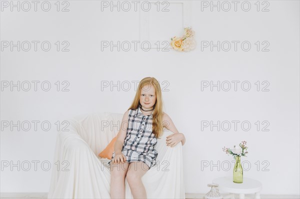 Smiling Middle Eastern girl sitting in armchair