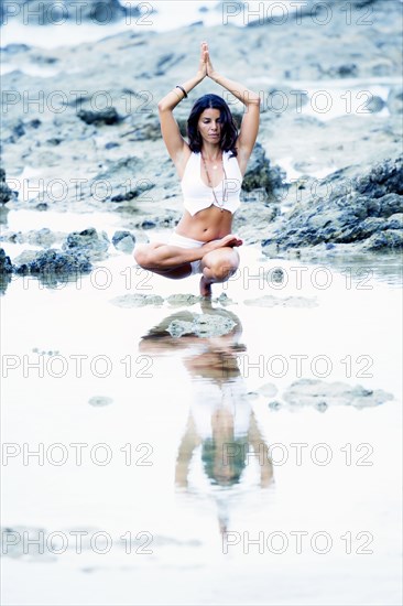 Woman practicing yoga in creek