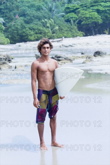 Man carrying surfboard on beach