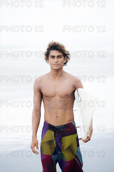 Man carrying surfboard on beach