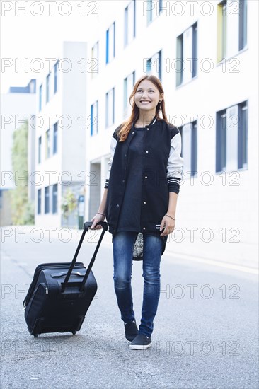 Mixed race woman rolling luggage