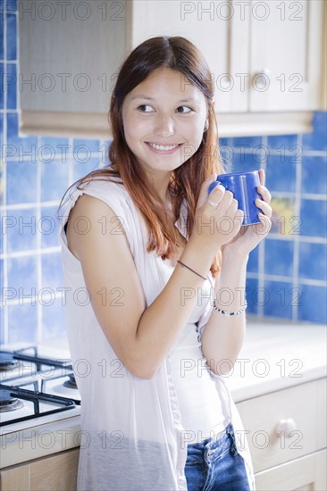 Mixed race woman drinking coffee in kitchen