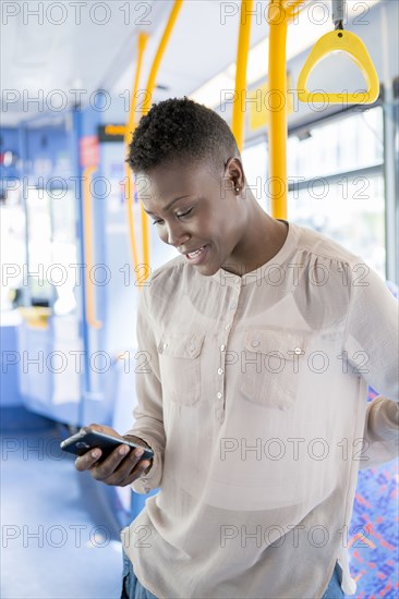 Black woman using cell phone on bus