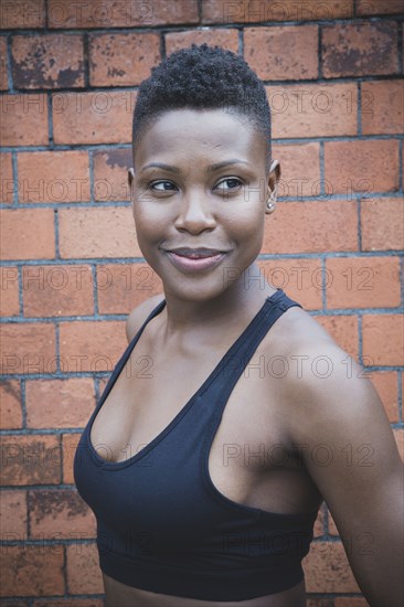 Black athlete smiling near brick wall