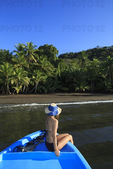 Hispanic woman sitting in boat near beach