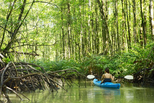 Hispanic woman rowing kayak on river