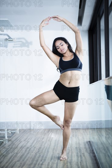 Hispanic woman practicing yoga in studio
